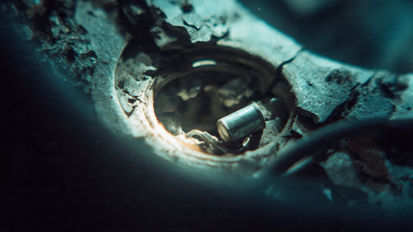 Close-up of a car steering wheel airbag compartment with exposed inflator components in harsh repair shop lighting